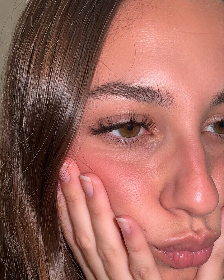 Close-up of a woman resting her face on her hands.